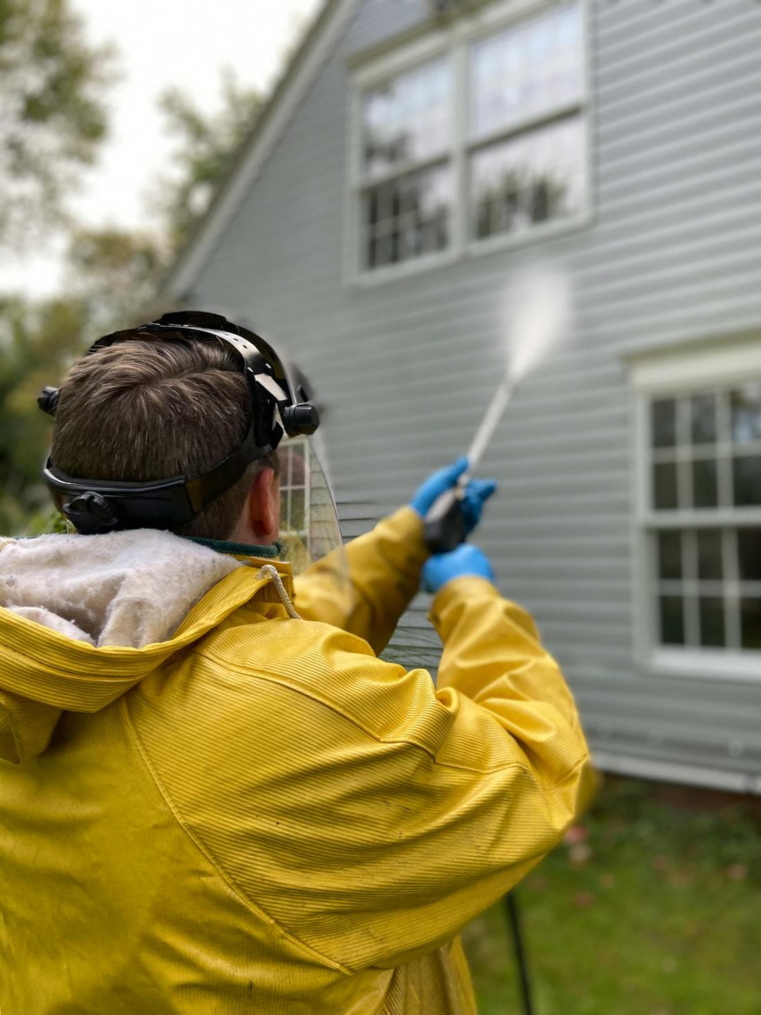 A worker pressure-washing house siding