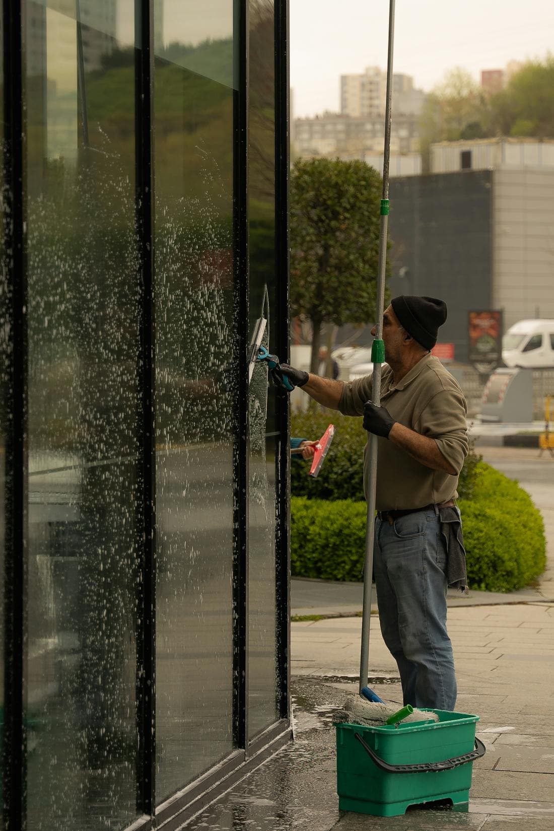 A professional window cleaner using a squeegee